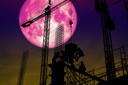full pink moon back silhouette worker on construction building.の写真素材