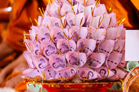 Banknotes are finely folded to decorate on the golen plate to give to the Buddhist temple in Kathin Ceremony of Thailandの写真素材