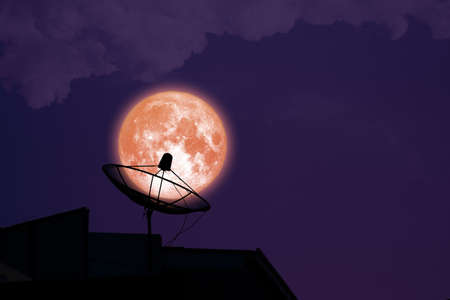 super full harvest blood moon on night sky back satellite dish on the roof
