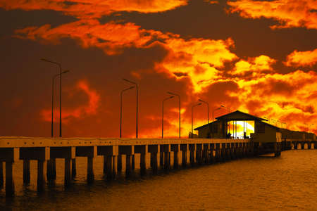 sunset sky red cloud on pavilion on pier and silhouette light poles