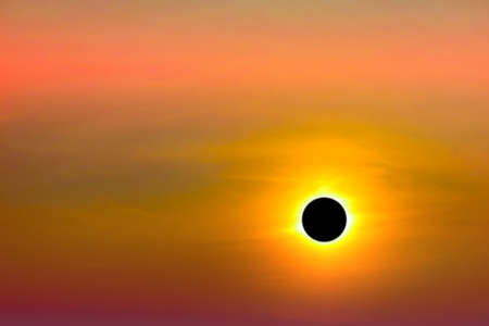 phenomenon of total sun eclipse over silhouette orange cloud and sunset skyの写真素材