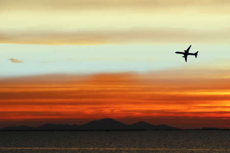 silhouette airplane on sky in sunset back on cloud white orange yellow red colorの写真素材