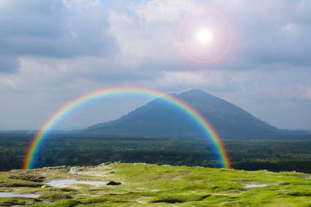 rainbow on the mountain and sun on the sky bacck white cloud over high mountainの写真素材
