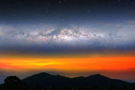 Milky way night landscape sunset light on silhouette mountain, space and stars on sky backgroundの写真素材