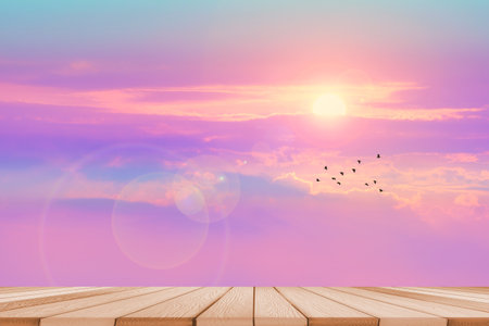 empty wood table top and blur sunset colorful pastel sky and silhouette flying birdsの写真素材