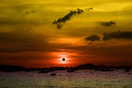 Eclipse on the sunset sky on the sea and silhouette speed boatの写真素材