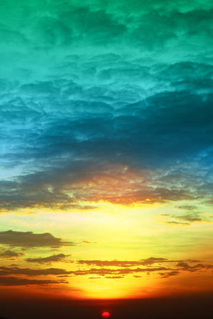 sunset colorful green blue yellow orange sky and dark cloudの写真素材