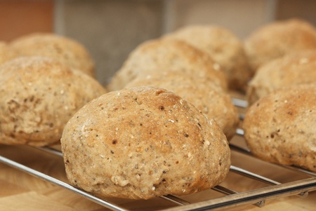 Close up of home made wholemeal bread rolls fresh from the oven, cooling on a wire rack, in a domestic kitchen settingの写真素材