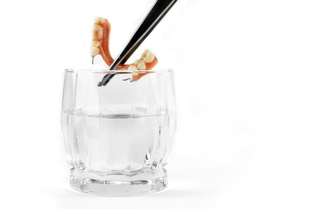 Denture being extracted with tweezers from a glass of waterの写真素材
