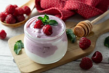 Healthy raspberry yoghurt garnished with fresh raspberries.の写真素材