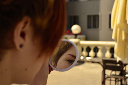 Woman paints eyelashes, look through the mirrorの写真素材
