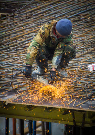 Construction worker cutting steel rods with electrical saw