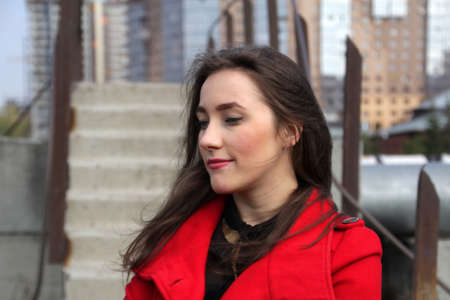 Beautiful girl in a red coat on the background of the stairs