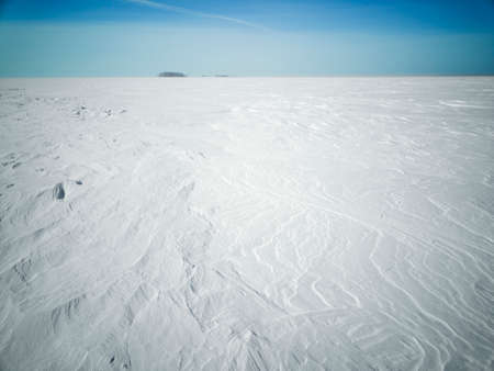 Beach in winter in Siberia. Snow and ice on the sea to the horizon, the island in the distanceの写真素材