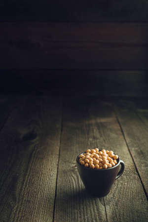 Close up soy beans in cup. Wooden background.の写真素材