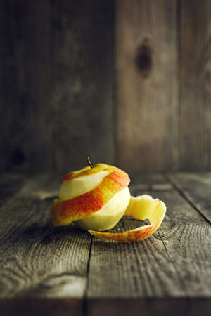 Apple with peeled skin on wooden backgroundの写真素材
