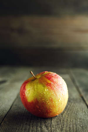 One Apple with water droplets on a wooden tableの写真素材