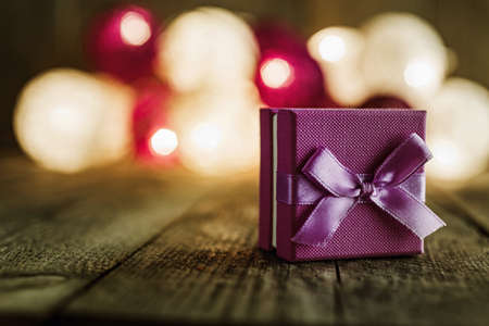 Christmas background with decorations and purple gift box on wooden board. Soft lights in the background.の写真素材