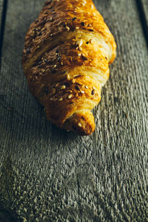 Crispy buttery croissants with seeds on old wooden tableの写真素材