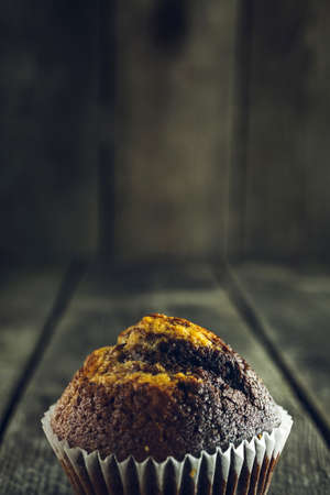 Tasty brown chocolate muffin on old wooden tableの写真素材