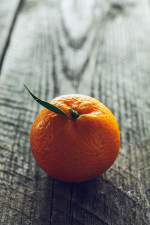Bright mandarin with small green leaf on a wooden backgroundの写真素材