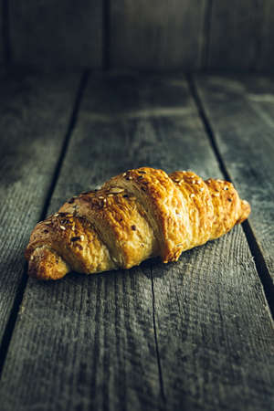 Crispy buttery croissants with seeds on old wooden tableの写真素材