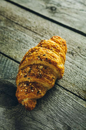 Crispy buttery croissants with seeds on old wooden tableの写真素材