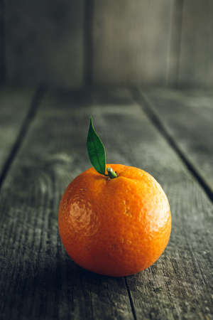 Bright mandarin with small green leaf on a wooden backgroundの写真素材