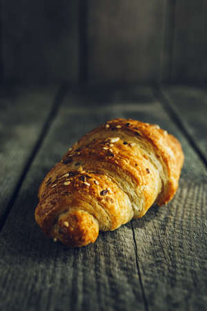 Crispy buttery croissants with seeds on old wooden tableの写真素材