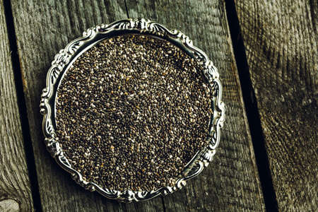 Super healthy chia seeds in silver plate on wooden backgroundの写真素材