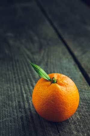 Bright mandarin with small green leaf on a wooden backgroundの写真素材