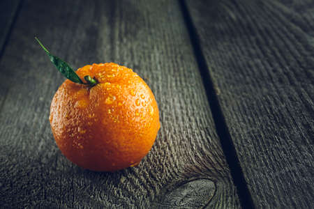 Bright mandarin with small green leaf on a wooden backgroundの写真素材