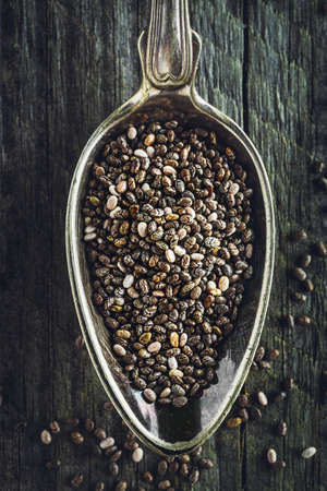 Spoon of healthy chia seeds on a wooden background. Macro shot.の写真素材