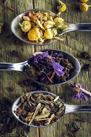Spoons of chamomile, peppermint and fireweed tea on a wooden background. Macro shot.の写真素材