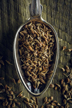 Dried anise seeds in a spoon on a wooden background. Macro shot.の写真素材
