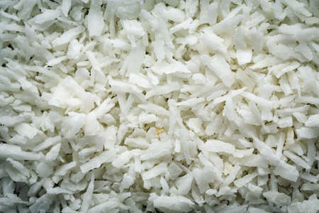 Desiccated coconut flakes macro background texture. Top view