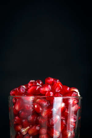 Ripe pomegranate seeds in a tiny glass on a vintage wooden backgroundの写真素材
