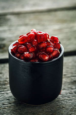 Ripe pomegranate seeds in a tiny glass on a vintage wooden backgroundの写真素材