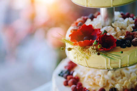 White wedding cake with flowers, strawberries, blueberries, raspberries and cranberriesの写真素材