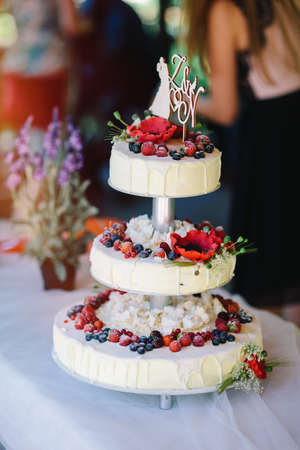 White wedding cake with flowers, strawberries, blueberries, raspberries and cranberriesの写真素材