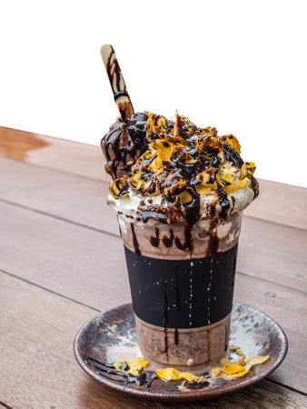 white background of chocolate milkshake in a plastic glass topping with cornflakes and whipped cream and ice creamの写真素材