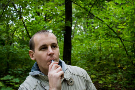 Man smoking electronic sigarette in the forestの写真素材