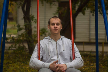 man sitting on a red swing thinkingの写真素材
