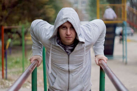 fitness, sport, exercising, training and lifestyle concept - young man doing triceps dip on parallel...