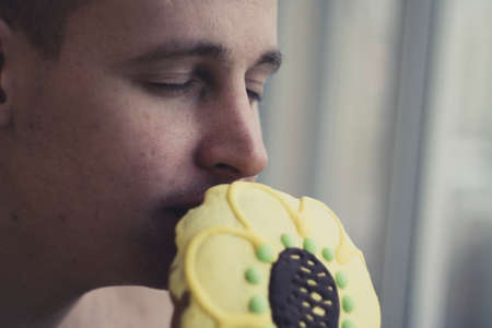 young man sniffing a beautiful and festive gingerbreadの写真素材