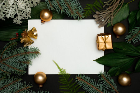 Christmas tree branches with paper card note. Creative layout with golden decorations on black background. Nature New Year concept.の写真素材