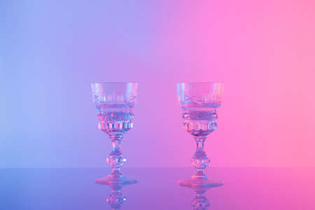 Glass against neon iridescent pink and blue colors. Minimal  party life concept.の写真素材