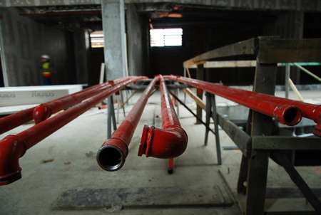 Red metal pipes on a building site lying on a rack waiting to be installed, close up view from the...