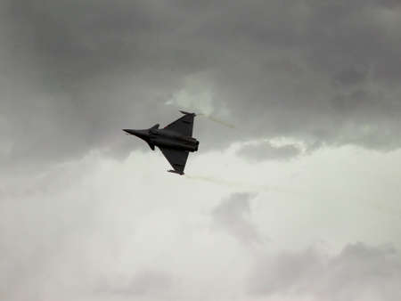 Dassalut Rafale is flying over our heads on the background of cloudy sky, visible jet trailsの写真素材