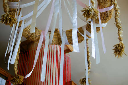 Interior decoration with hanging white ribbons attached to a hoop or ring made of dried straw or grass bound into a circle with plaited cords of straw hanging downの写真素材